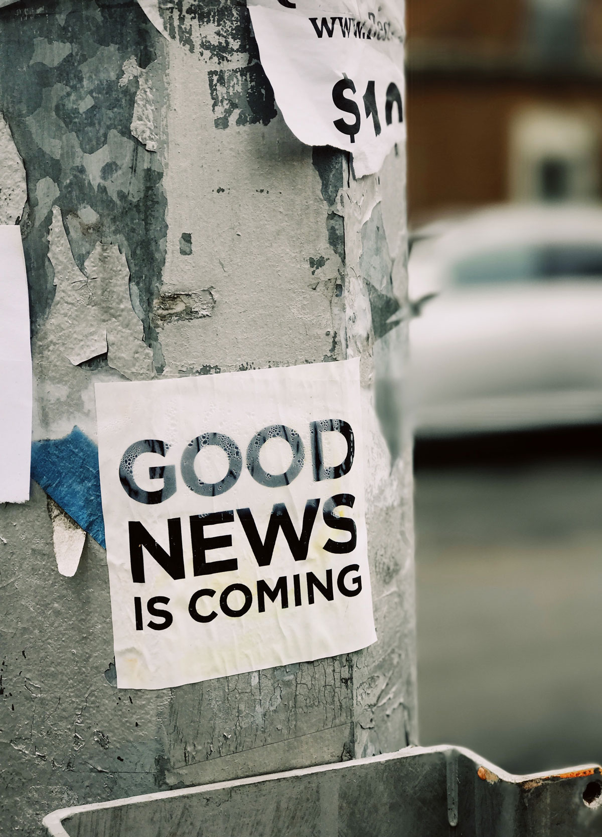 Aufkleber "Good News is coming" auf Säule draußen