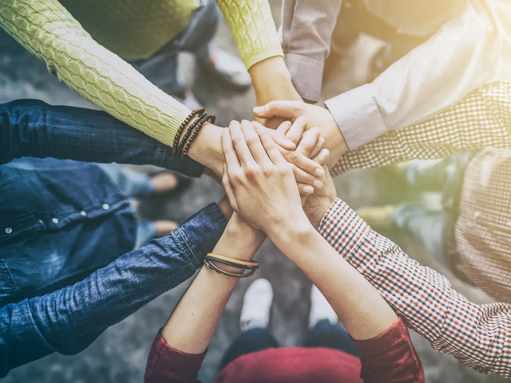 Teamwork: Mitarbeiter stehen im Kreis und legen Hände aufeinander