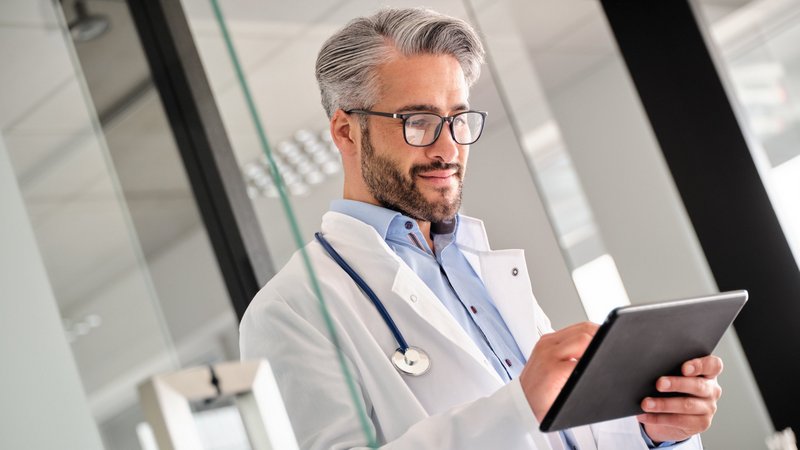 IT-Sicherheit und Datenschutz: Arzt bedient Tablet im Krankenhausflur
