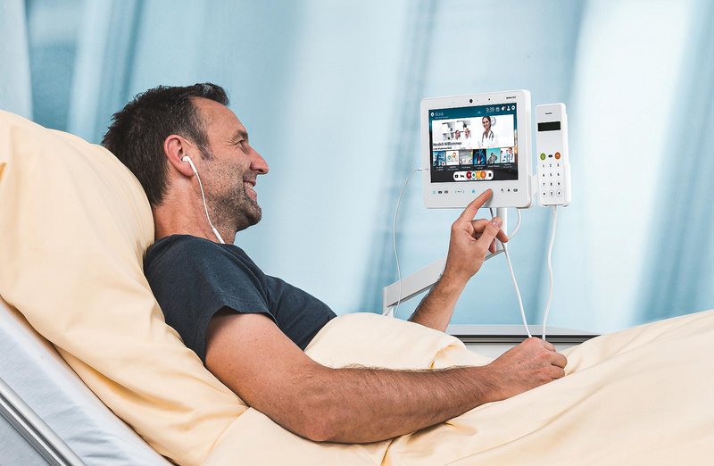 ConnectedCare Unternehmensgeschichte | Patient im Krankenhausbett bedient ConnectedCare Tablet MediPaD